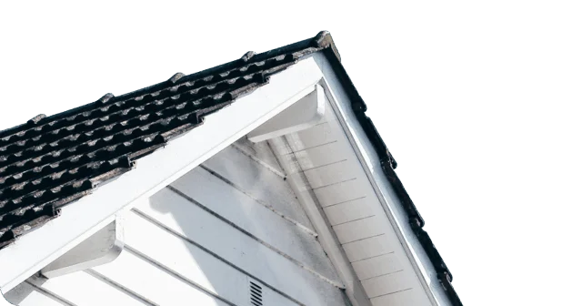 A close-up of the gable end of a house with white siding and a black tiled roof against a white background.