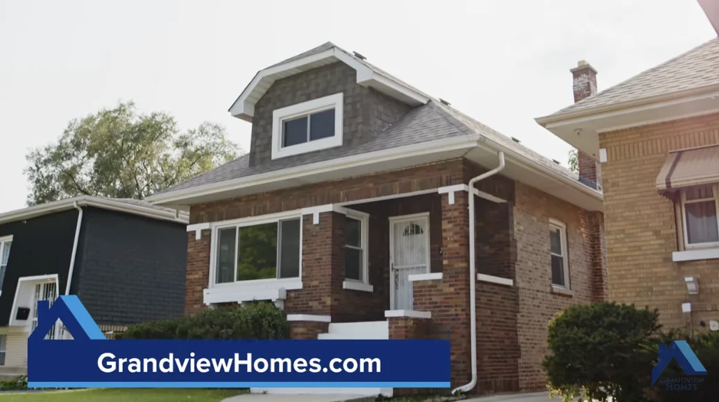 A brick house with white trim and a small front porch; a banner at the bottom displays "GrandviewHomes.com" and a blue logo.