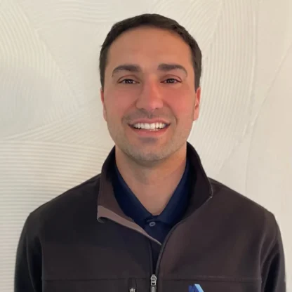A man wearing a black zip-up jacket with the "Grandview Homes" logo stands in front of a light-colored textured wall, smiling at the camera.