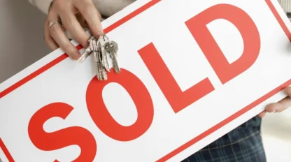 A person holding keys and a signboard