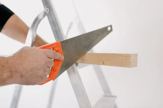 Crop man sawing wooden plank