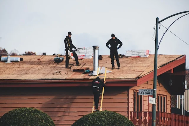 men standing on a roof repairing a house